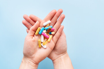 The girl holds a handful of brightly colored vitamins, nutritional supplements, and medicines in her palms. Concept of medicine and health support.