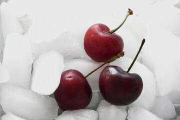 Cherries with ice cubes. Background freshness. Chunks of fresh frozen fruit. 