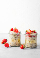 Overnight Oats with Fresh Strawberry, Banana and Chia Seeds in Jars on Light Grey Background, Healthy Snack or Breakfast