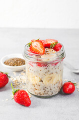 Overnight Oats with Fresh Strawberry, Banana and Chia Seeds in Jars on Light Grey Background, Healthy Snack or Breakfast