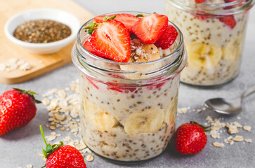 Overnight Oats with Fresh Strawberry, Banana and Chia Seeds in Jars on Light Grey Background, Healthy Snack or Breakfast
