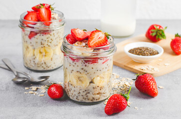 Overnight Oats with Fresh Strawberry, Banana and Chia Seeds in Jars on Light Grey Background, Healthy Snack or Breakfast