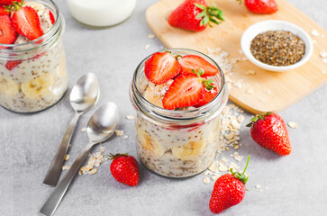Overnight Oats with Fresh Strawberry, Banana and Chia Seeds in Jars on Light Grey Background, Healthy Snack or Breakfast