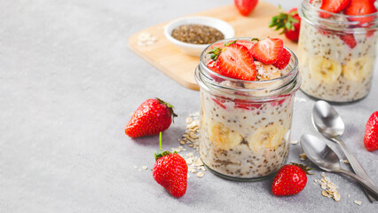 Overnight Oats with Fresh Strawberry, Banana and Chia Seeds in Jars on Light Grey Background, Healthy Snack or Breakfast