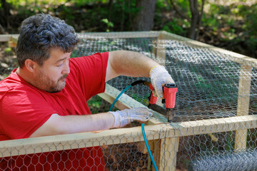 Worker frame by nailing metal mesh with build montage new wooden domestic chicken coop on farm © ungvar
