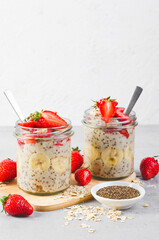 Overnight Oats with Fresh Strawberry, Banana and Chia Seeds in Jars on Light Grey Background, Healthy Snack or Breakfast