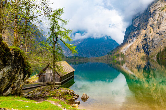 Lonely boathouse on Obersee surrounded by mighty mountains shrouded in mythical mist