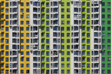 Multi-colored wall of an apartment building with the same type of windows and balconies