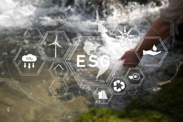 ESG icons concept on blurred river with woman hand. Environment, society and governance. 