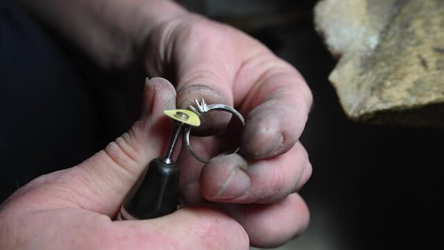 Gold wedding ring craft by goldsmith, isolated. Macro video. Craft jewelry making with professional tools. Process of ring polishing making handmade. 4k raw slow motion video