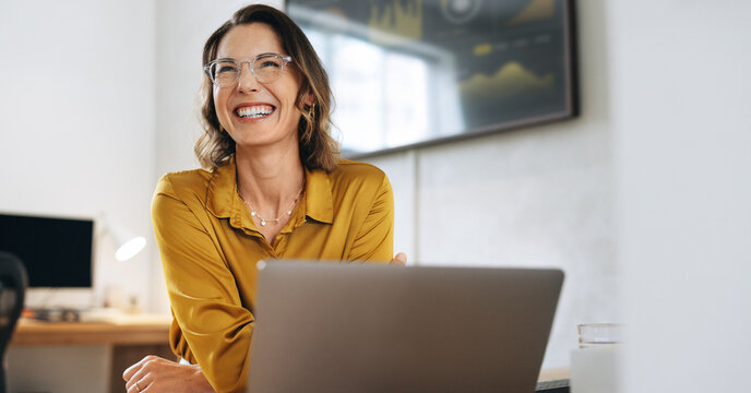 Confident businesswoman with eyeglasses laughing in her office