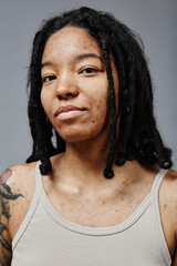 Vertical portrait of black young woman with no makeup and real skin texture looking at camera in...