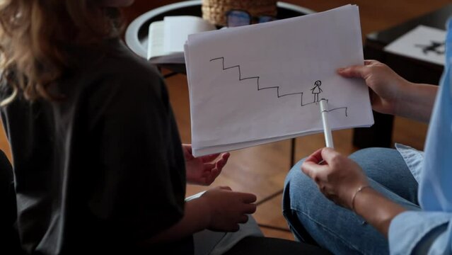 A girl at a psychologist's appointment draws a test drawing, low self-esteem and psychological problems in a child, a photo from the back.