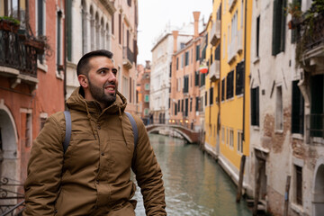 Fototapeta na wymiar Young tourist man with beard on the canals of Venice among colorful facades