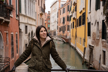 Fototapeta na wymiar Young woman tourist on a Venice canal bridge amidst colorful facades