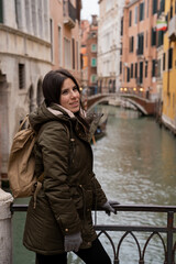 Young woman tourist on a Venice canal bridge amidst colorful facades