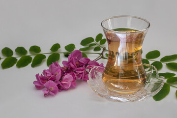 Lilac colored Acacia flower tea on white background