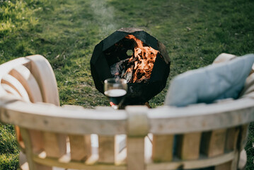 Wooden bench with Wine gall and a fire bucket on the grass in the garden at night