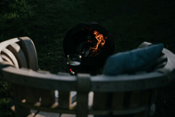 Wooden bench with Wine gall and a fire bucket on the grass in the garden at night