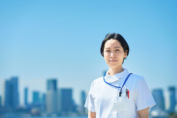 晴天の街並みの前に立つ白衣の女性