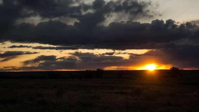 Time lapse sun setting through rain clouds on prairie