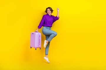 Full length photo of wearing purple shirt bob hair woman fist up hold baggage shopping before flight isolated on yellow color background