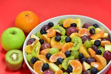 Healthy fresh fruit salad bowl on red background. Top view. Healthy food concept, healthy high vitamin fruit, Thai fruits, mixed fruit background.