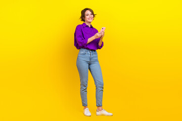 Full body photo of cheerful entrepreneur hold smartphone browsing safari google internet online isolated on yellow color background