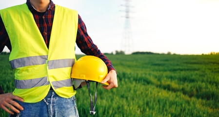 Construction worker holding yellow hard hat and wearing yellow fluorescent waistcoat. Electrician...