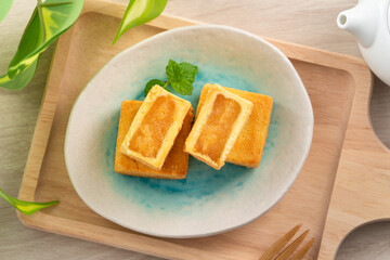 Delicious pineapple cake pastry in a plate on wooden table background with tea.