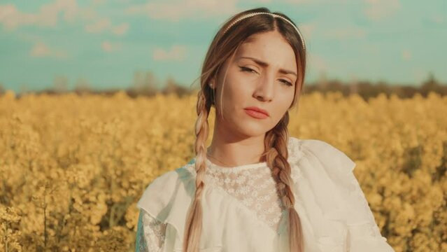 Beautiful young woman in white dress on yellow flower meadow in sunset