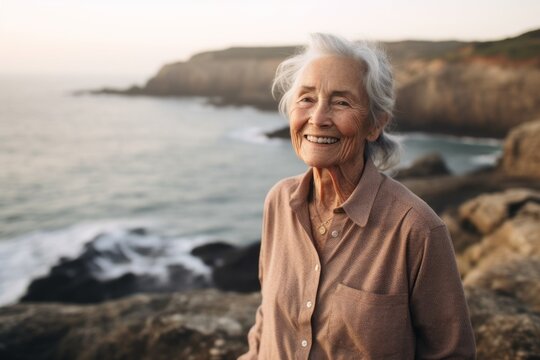 Medium shot portrait photography of a satisfied old woman wearing an elegant long-sleeve shirt against a dramatic coastal cliff background. With generative AI technology