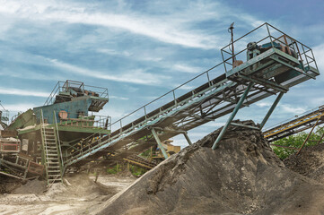 Crushing machinery, cone type rock crusher, conveying crushed granite gravel stone in a quarry open pit mining..