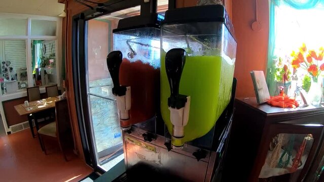 Slurpee machine turning inside of a corner store during the day.