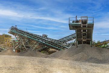 Crushing machinery, cone type rock crusher, conveying crushed granite gravel stone in a quarry open pit mining..