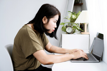 concept of Asian woman with Kyphosis: side view of laptop Work with hunched back, forward head posture, and spinal curvature - obrazy, fototapety, plakaty