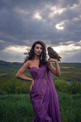 Obraz premium Beautiful woman with owl in purple dress in nature