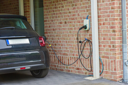 Ein Elektroauto tankt an der h&auml;uslichen Ladestation im Carport