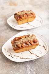 Caramel and almond cake on brown concrete, side view, close up.
