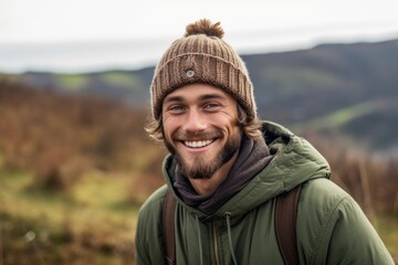 Naklejka na ściany i meble Lifestyle portrait photography of a grinning boy in his 30s wearing a warm beanie or knit hat against a picturesque countryside background. With generative AI technology