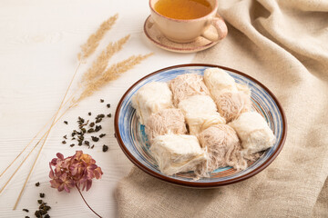 traditional arabic sweets pishmanie and a cup of green tea on white wooden,  side view.