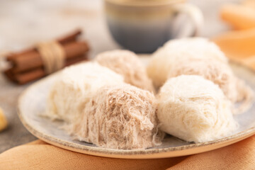 traditional arabic sweets pishmanie and a cup of coffee on brown concrete, side view, selective focus.