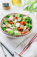 Healhty tuna salad with tomato, quail eggs, lettuce and salad dressing with olive oil, lemon juice and grain mustard.
