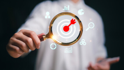 Businesswoman using magnifying glass focus to target icons for planning development leadership and customer target group concept.