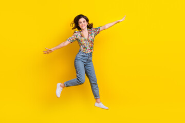 Fototapeta na wymiar Full size photo of jumping fly hands wings girl wearing trendy flowers print summer blouse lightweight isolated on yellow color background