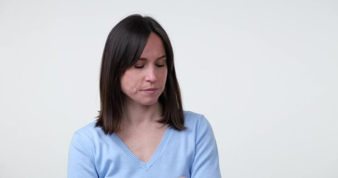 A Caucasian woman standing on a white background, scratching her head and looking around with a bored expression. She seems frustrated and doesn't know what to do with herself.