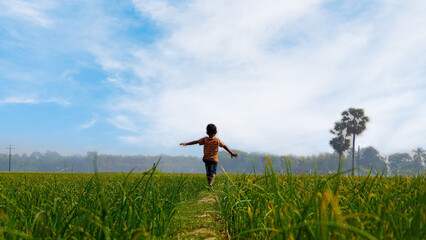 A child dances with nature on a rural path. Children in the village of Bangladesh play in the field.