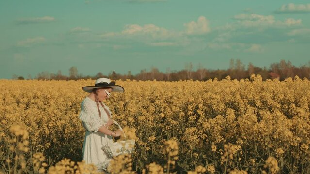 Beautiful young woman in white dress on yellow flower meadow in sunset