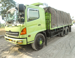 Green colored flatbed heavy trucks used to transport and distribute cements sacks from factory to...