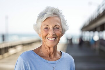 Environmental portrait photography of a happy old woman wearing a casual short-sleeve shirt against a scenic beach pier background. With generative AI technology